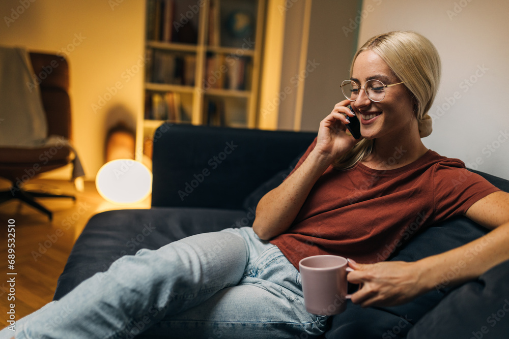 Obraz premium Beautiful blond woman having a pleasant phone call from home.