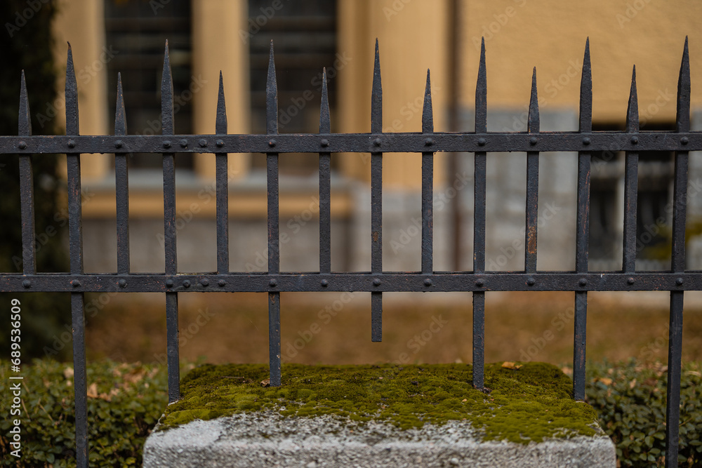 Frontal view of Black metal steel fence in a city. Rustical vintage style fence with spiked tops and rivets visible. Frontal view of Black metal steel fence in a city. Rustical vintage style fence with spiked tops and rivets visible.