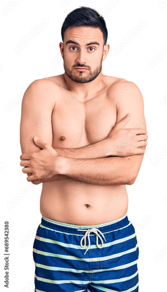 Fototapeta premium Young handsome man wearing swimwear shaking and freezing for winter cold with sad and shock expression on face