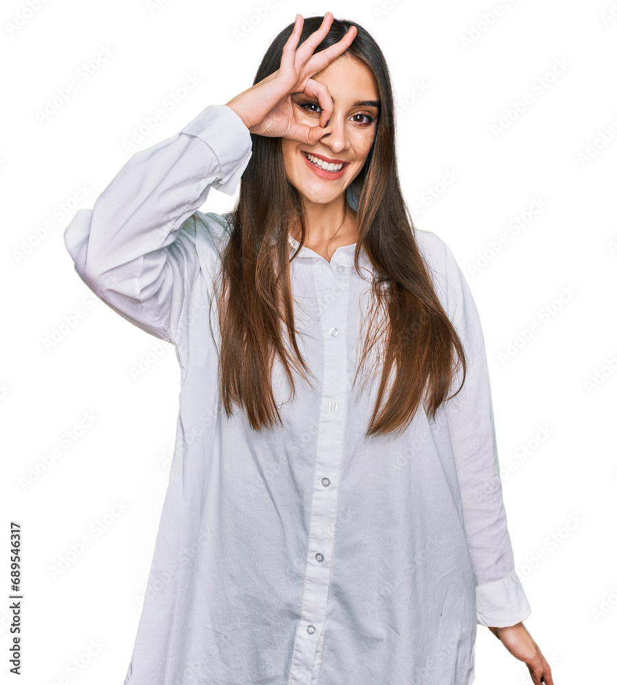 Young beautiful woman wearing casual white shirt smiling happy doing ok sign with hand on eye looking through fingers