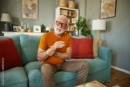 Foto Elderly man suffering from his wrist joint pain at home