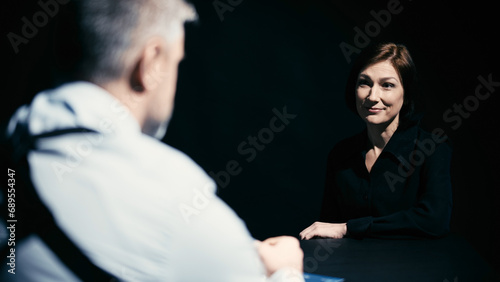 A suspected woman is smiling while listening to the detective's variants of the crime during interrogation