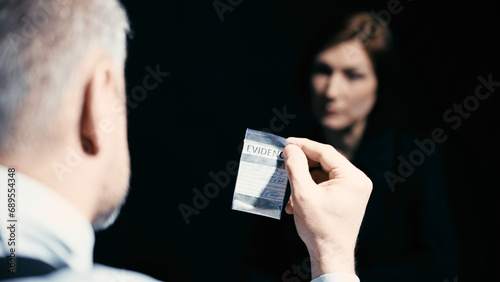 A detective is showing an evidence bag with an illegal substance to an interrogated woman photo