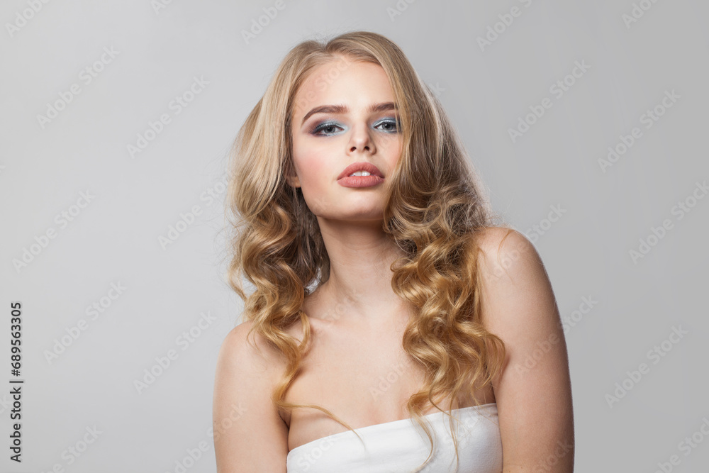 Young female face. Blonde woman with long curly hair and makeup studio portrait Young female face. Blonde woman with long curly hair and makeup studio portrait