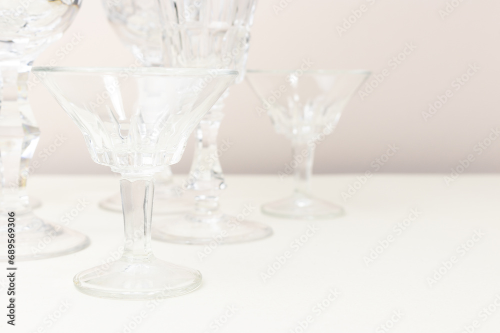 Obraz premium Crystal glasses in front of beige background. Minimal composition.
