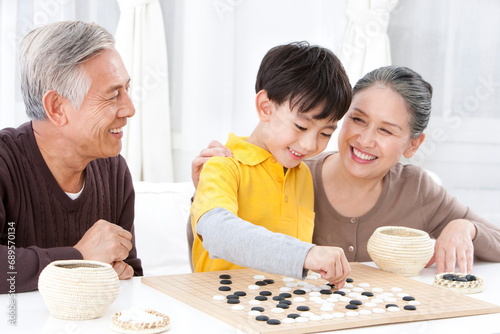 Chinese grandparents and grandson playing the game of Go photo
