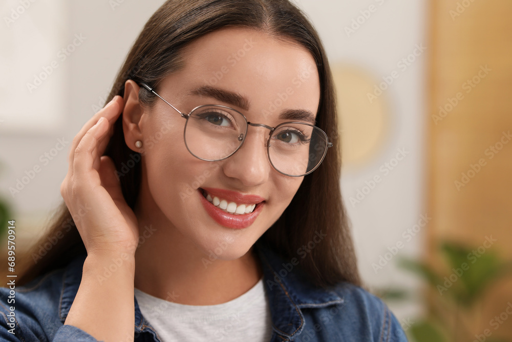 Portrait of beautiful young woman with glasses indoors. Attractive lady smiling and looking into camera Portrait of beautiful young woman with glasses indoors. Attractive lady smiling and looking into camera