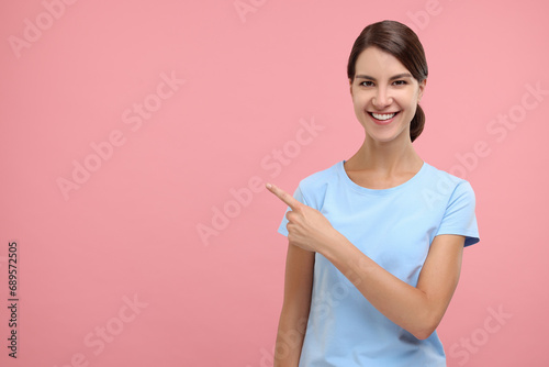 Special promotion. Happy woman pointing at something on pink background, space for text