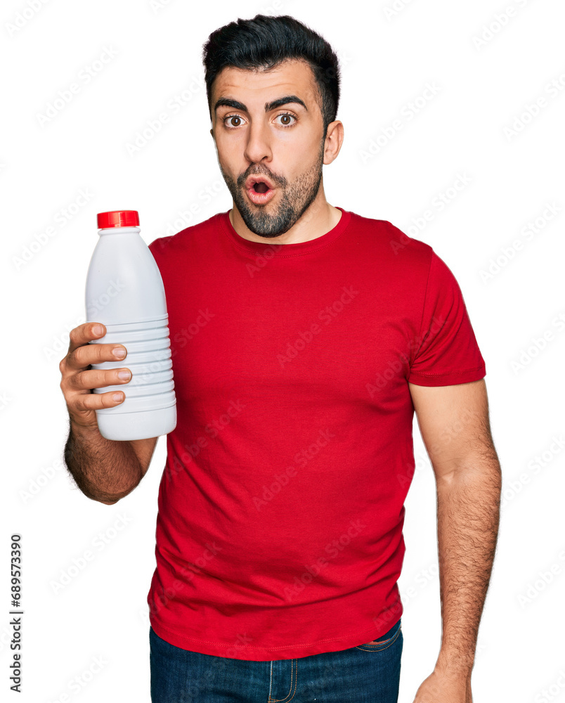 Hispanic man with beard holding liter bottle of milk scared and amazed with open mouth for surprise, disbelief face Hispanic man with beard holding liter bottle of milk scared and amazed with open mouth for surprise, disbelief face
