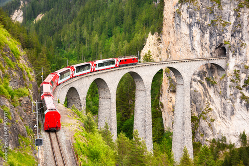 Swiss red train on viaduct in mountain, scenic ride photo
