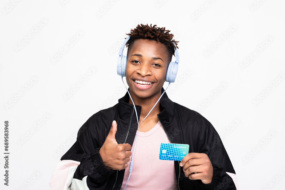 Delighted dark skinned black guy in headphones smiling showing thumb up. My first credit card happy customer service concept over white background in studio isolated smiling.