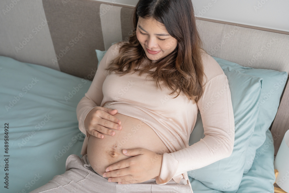 Pregnant asian woman holds hands on belly touching her baby caring about her health Beautiful happy pregnant woman tender mood photo of pregnancy Pregnant asian woman holds hands on belly touching her baby caring about her health Beautiful happy pregnant woman tender mood photo of pregnancy