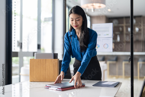 Quit Job asian business woman sending resignation letter and packing Stuff Resign Depress or carrying business cardboard box in office. Change of job or fired from company photo