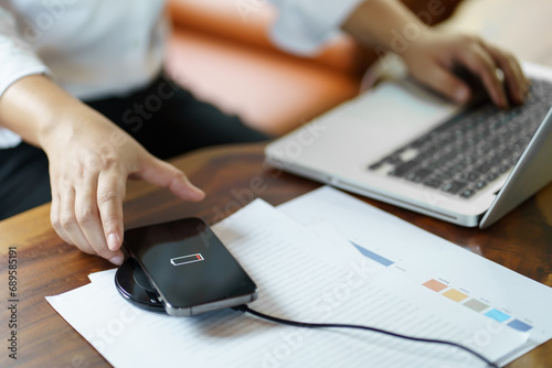 Charging mobile phone battery with wireless charging device in the table. Smartphone charging on a charging pad. Mobile phone near wireless charger Modern lifestyle technology concept