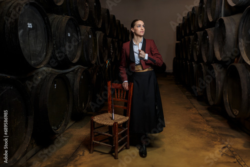 Young woman venenciador standing in wine cellar in light photo