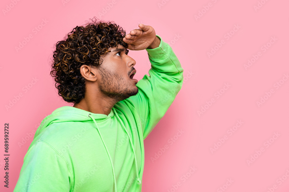 Side photo of young funny guy wearing green sweatshirt touch forehead look far away copyspace information isolated on pink color background Side photo of young funny guy wearing green sweatshirt touch forehead look far away copyspace information isolated on pink color background