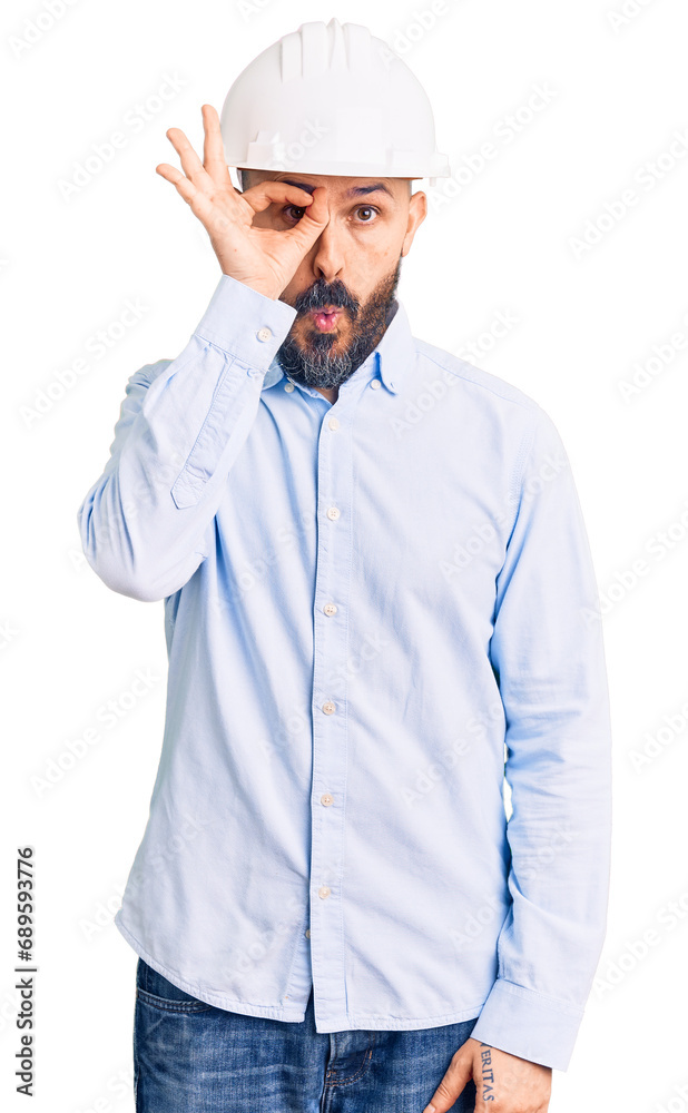 Young handsome man wearing architect hardhat doing ok gesture shocked with surprised face, eye looking through fingers. unbelieving expression. Young handsome man wearing architect hardhat doing ok gesture shocked with surprised face, eye looking through fingers. unbelieving expression.