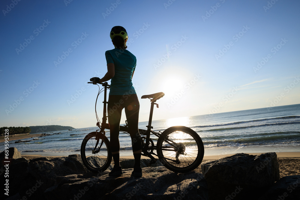 Riding folding bike on sunrise seaside road