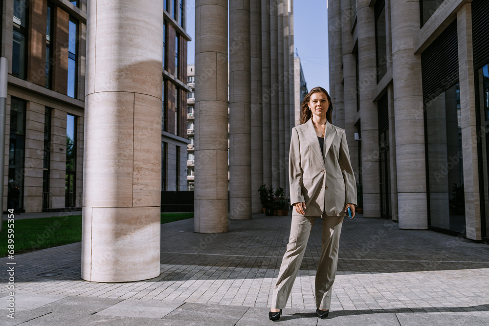 Purposeful brunette female lawyer standing at building with huge columns looks at camera feels confidence ready for any situations, independent women.