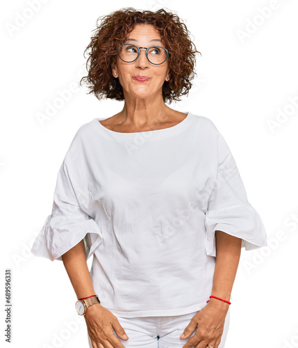 Beautiful middle age mature woman wearing casual clothes and glasses smiling looking to the side and staring away thinking.