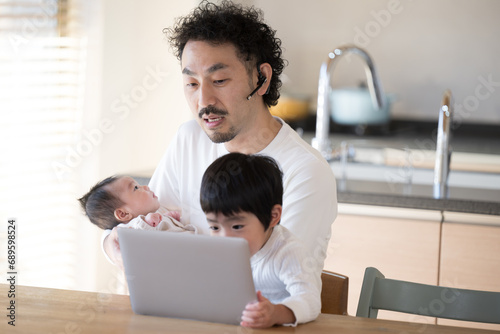  赤ちゃんをだっこするお父さん　リモートワークは無理そう「パパの代わりに会議でてあげる」助けようとしているけど大丈夫ですのシーン photo