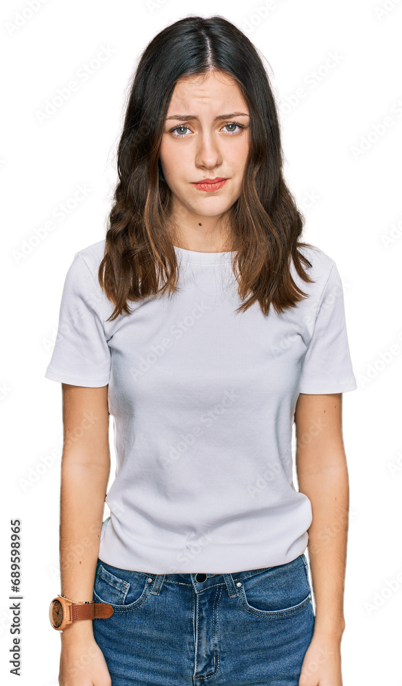 Young beautiful woman wearing casual white t shirt skeptic and nervous, frowning upset because of problem. negative person. Young beautiful woman wearing casual white t shirt skeptic and nervous, frowning upset because of problem. negative person.