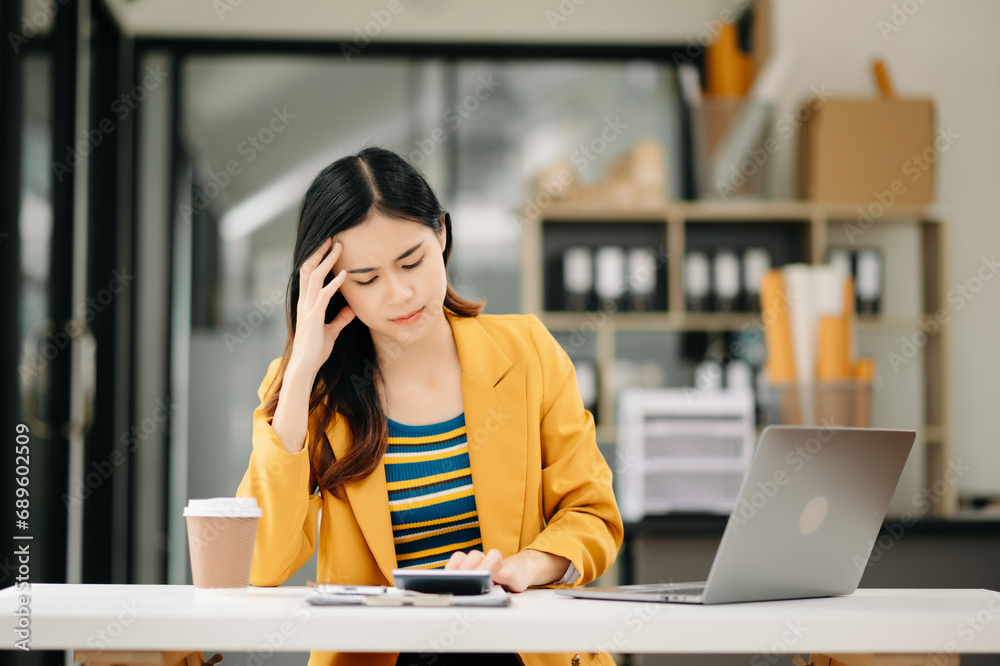 Fototapeta premium Asian business woman is stressed, bored, and overthinking from working on a tablet at the office.