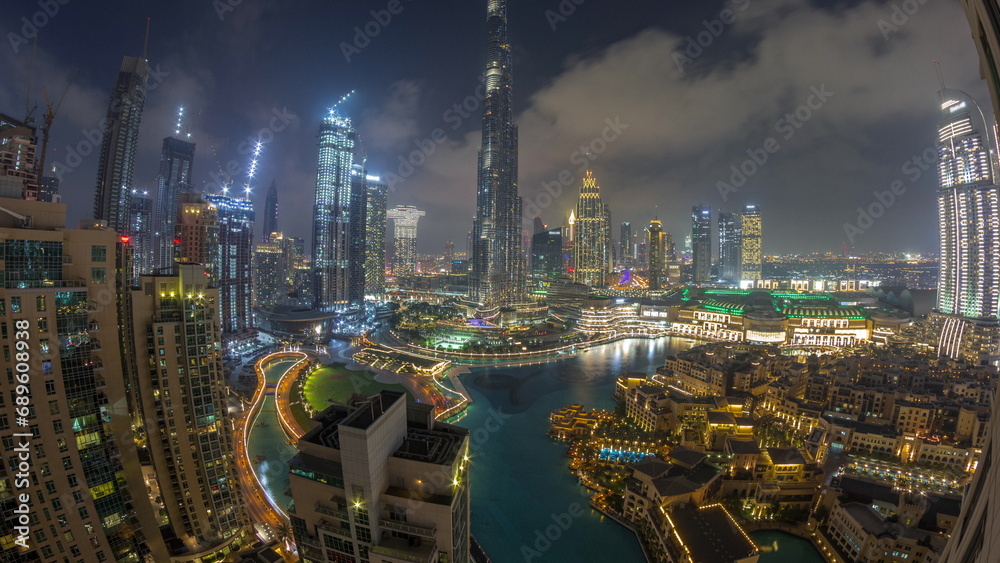 Skyscrapers rising above Dubai downtown day to night timelapse surrounded by modern buildings aerial top view