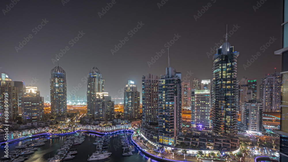 Panorama showing Dubai marina tallest skyscrapers and yachts in harbor aerial night timelapse.