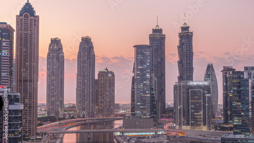 Cityscape with skyscrapers of Dubai Business Bay and water canal aerial day to night timelapse.