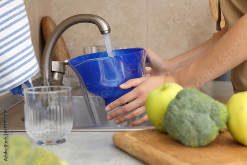 A water filter stands in the kitchen with fresh vegetables photo