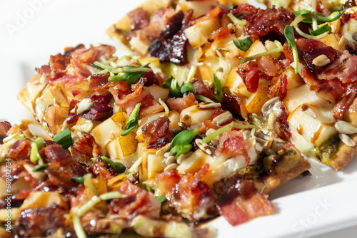 Delicious pizza with pesto bacon pears brie cheese cranberries sunflower sprout and seeds with balsamic photo