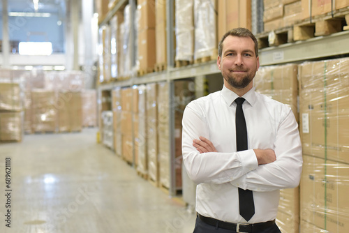 portrait friendly businessman/ manager in suit working in the warehouse of a company