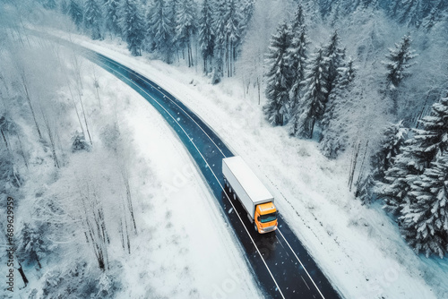 Aerial view of a semi truck moving on the winding road with wet surface and snow. Transportation during winter.