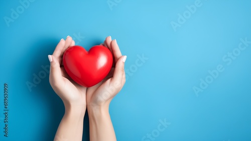 A pair of human hands gently cradling a vibrant red heart symbol  representing support for heart disease awareness and the importance of cardiovascular health care.