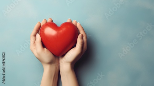 A pair of human hands gently cradling a vibrant red heart symbol, representing support for heart disease awareness and the importance of cardiovascular health care. photo