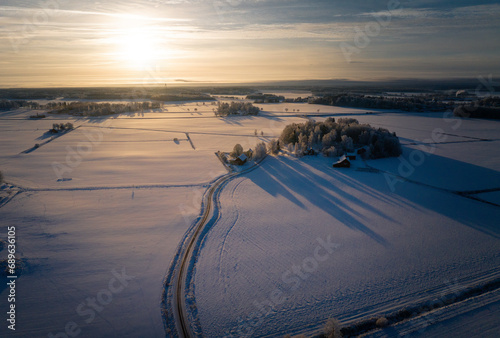 Winter Wonderland Sunrise: Majestic Aerial View of a Swedish Landscape with a Serene Roadway Cutting Through the Frozen Beauty (ID: 689636105)