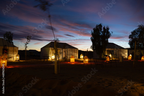 Luxury camp in the Sahara desert, with lights and the typical Haimas. Photo taken at dusk.