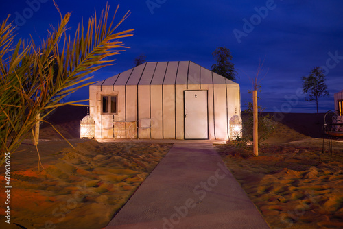 Luxury camp in the Sahara desert, with lights and the typical Haimas. Photo taken at dusk.