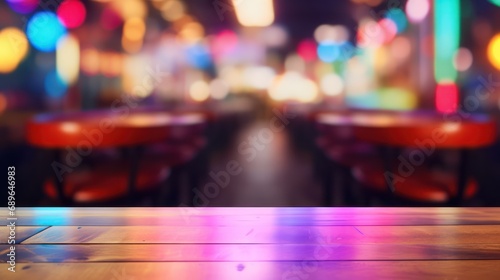 Empty wood table top on abstract blurred game center shop and nightclub lights background 