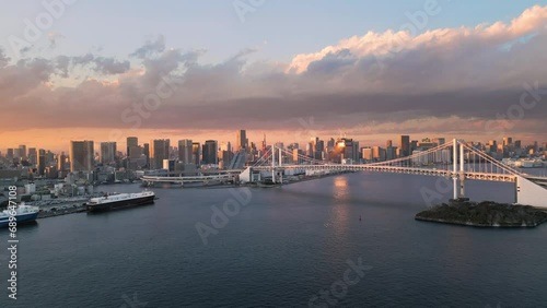 tokyo city bay aerial view drone at sunset flying to rainbow bridge modern building and skyscrapers on the seafront in the background photo