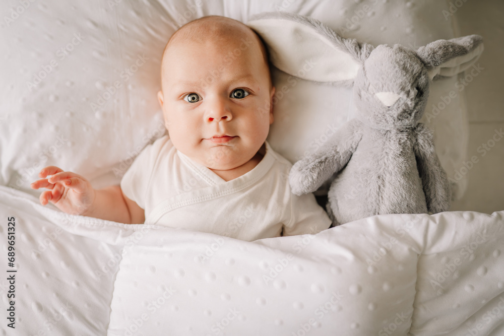 The baby is lying in his crib and looking at the camera . A happy child. Children's article. Copy Space The baby is lying in his crib and looking at the camera . A happy child. Children's article. Copy Space