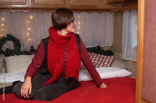 A woman in casual clothes lies on a bed in a room decorated for Christmas