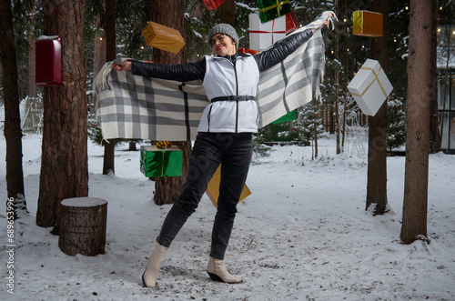 Woman standing among Christmas gifts hanging from tree branches