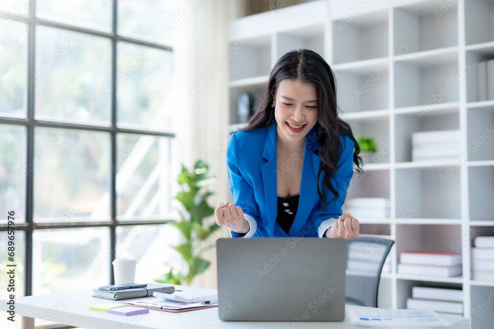 Excited cheerful asian business woman using laptop computer in the office, getting good news, feeling joy, laughing, making winner gesture, happy to win prize. Excited cheerful asian business woman using laptop computer in the office, getting good news, feeling joy, laughing, making winner gesture, happy to win prize.