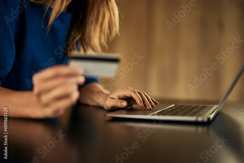 Foto Side view of a woman entering data into the laptop, buying something online, and holding a credit card