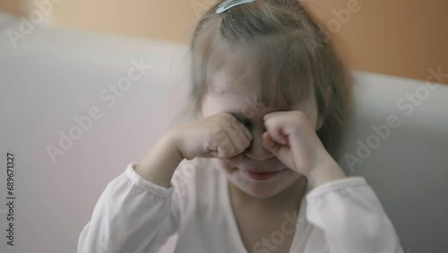 little girl rubs her eyes with her hands photo