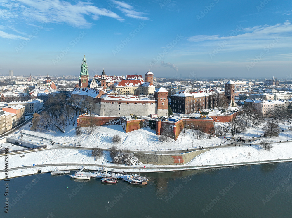 Wawel Castle, Cathedral and Vistula river in winter. Krakow, Poland. Royal Wawel Cathedral and castle with snow in winter. Vistula river and tourist boats. Aerial view with boulevard, promenades - obrazy, fototapety, plakaty 