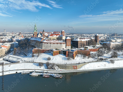 Wawel Castle, Cathedral and Vistula river in winter. Krakow, Poland. Royal Wawel Cathedral and castle with snow in winter. Vistula river and tourist boats. Aerial view with boulevard, promenades
