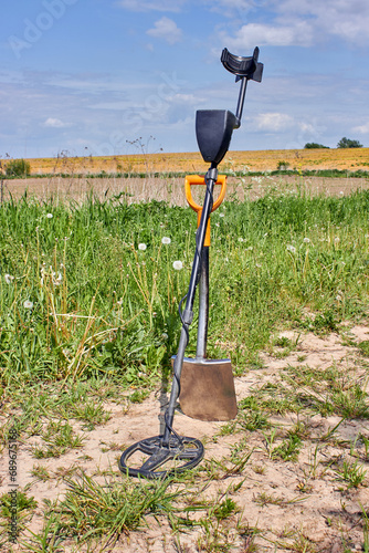 Crossed shovel and magnetic metal detector against the backdrop of a beautiful natural landscape. photo